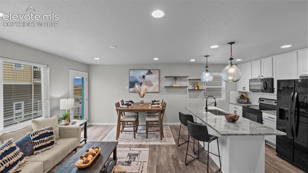 Image 9 of 34: Open-concept kitchen featuring an island with stone-finish countertops, whi