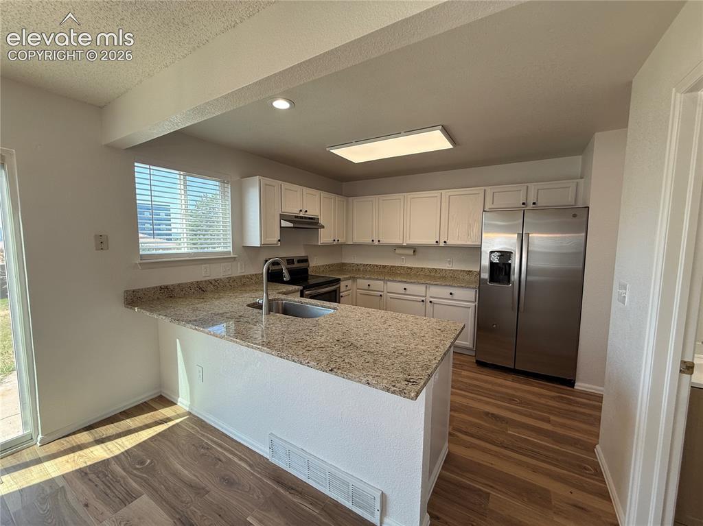 Image 10 of 20: Open-concept kitchen featuring an island with an undermount sink, granite c
