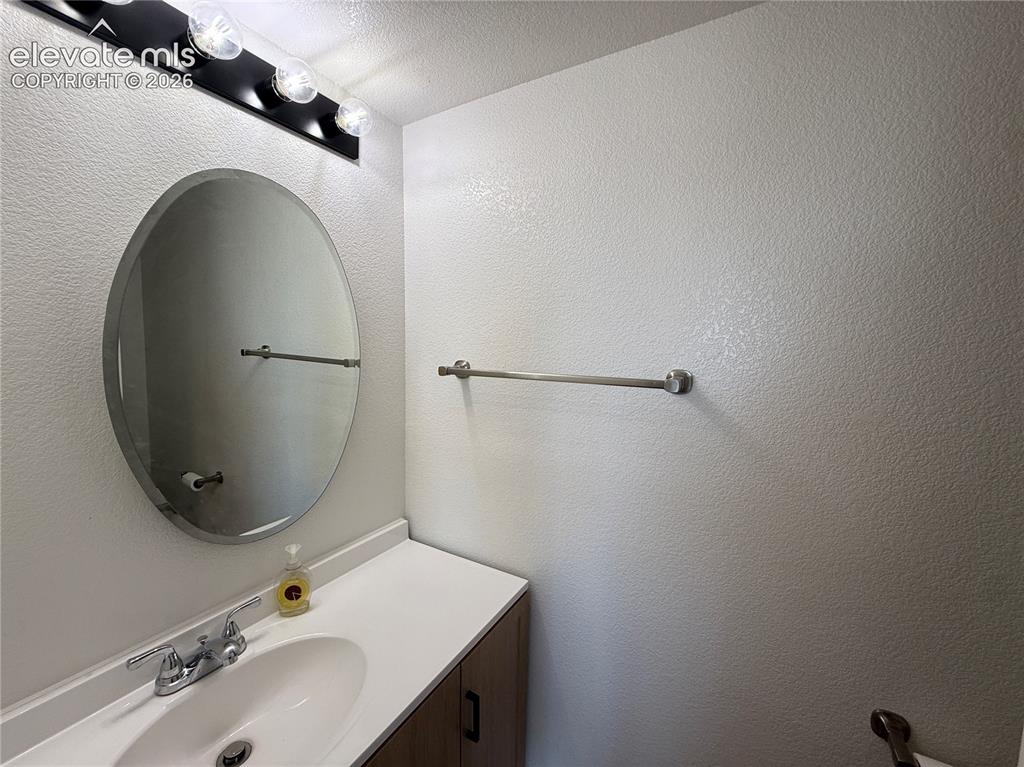 Image 12 of 20: Bathroom vanity featuring a white countertop, oval undermount sink, and woo