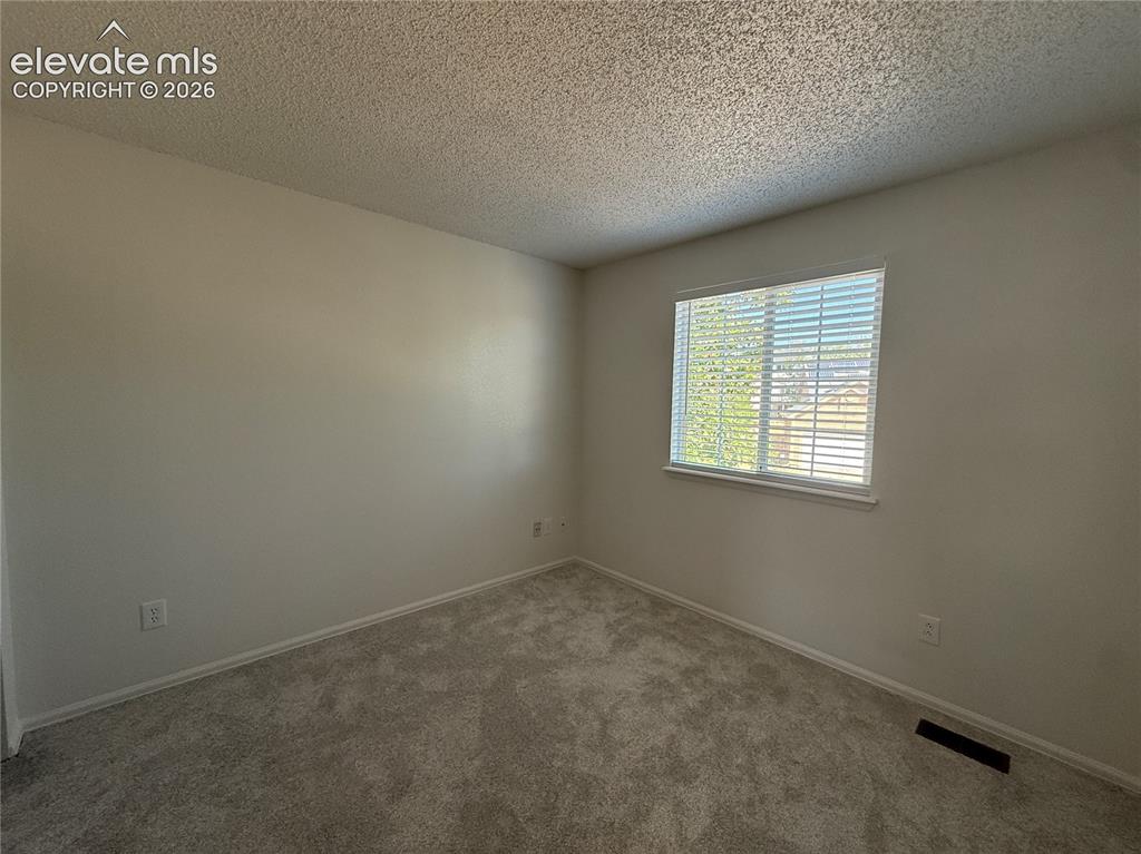 Image 17 of 20: Bright room featuring a window with horizontal blinds, neutral-toned walls,