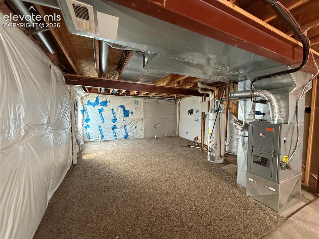 Image 18 of 20: Basement utility space featuring a furnace, two water heaters, exposed duct