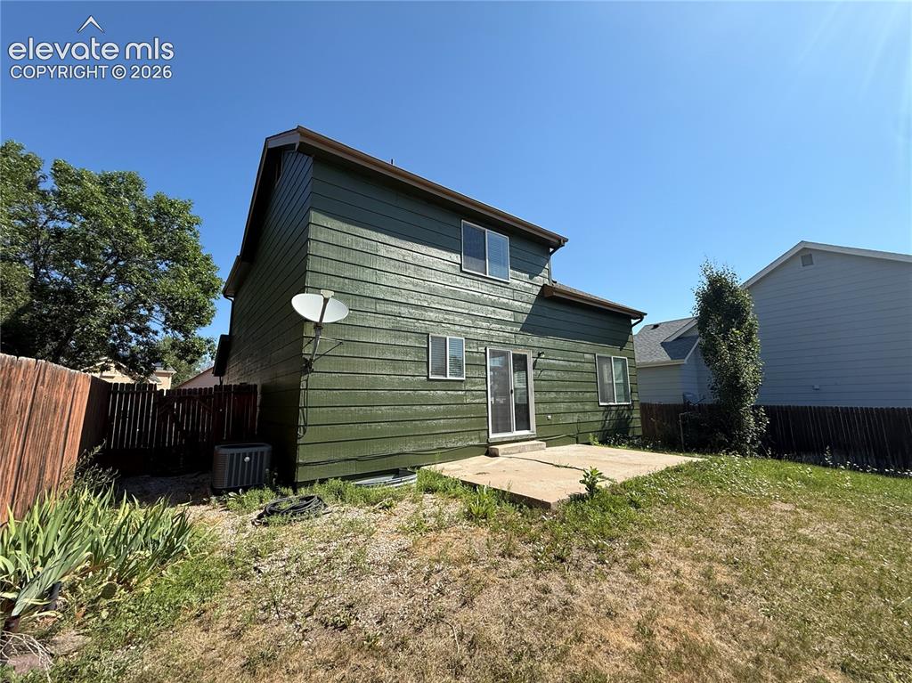 Image 19 of 20: Green siding exterior featuring multiple windows and a concrete patio