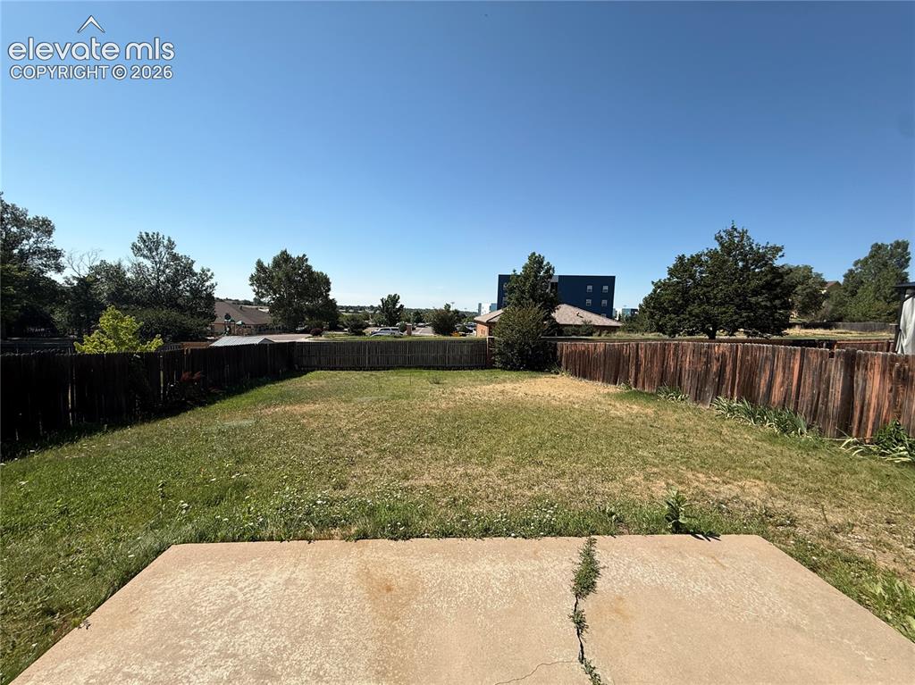 Image 20 of 20: Expansive backyard featuring a concrete patio, wood fencing, and mature tre