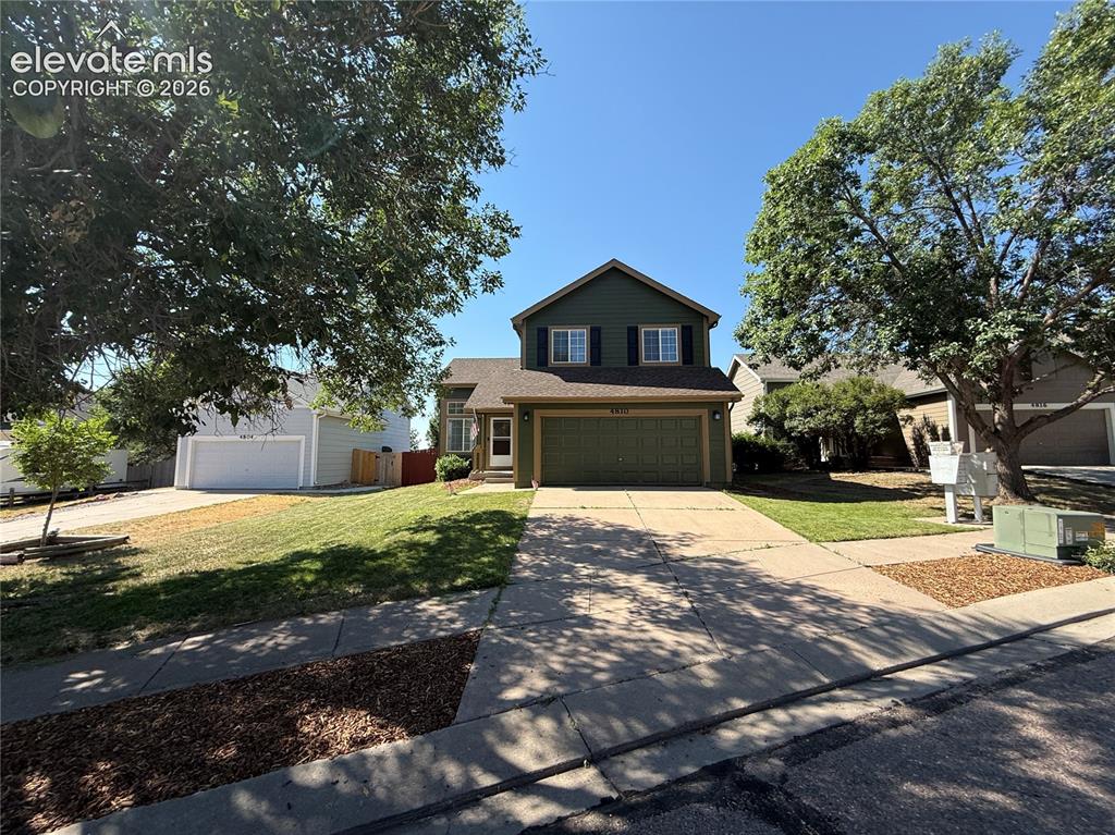 Image 3 of 20: Two-story residence featuring a green exterior with white trim and dark win