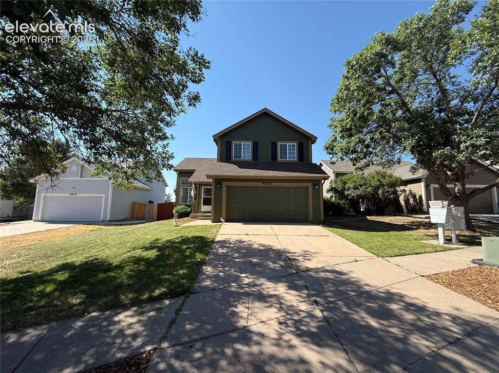 Image 4 of 20: Two-story residence featuring a dark green exterior, black shutters, and an