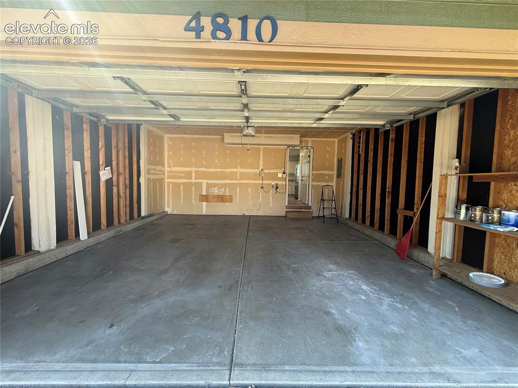 Image 6 of 20: Two-car garage with a concrete floor, exposed wood framing, and integrated