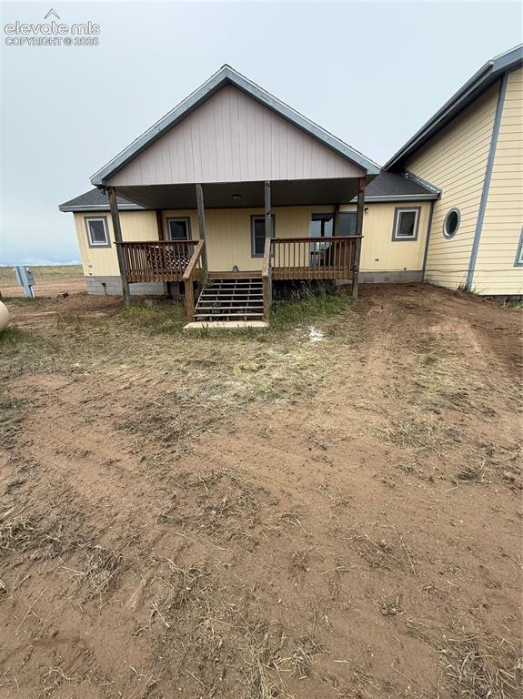Image 17 of 19: Rear exterior with a covered porch, wood-tone decking, and a sloped rooflin