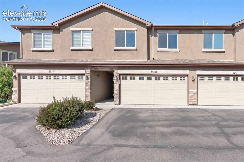 Image 1 of 42: Stucco exterior with stone accents, multiple large windows, and an attached