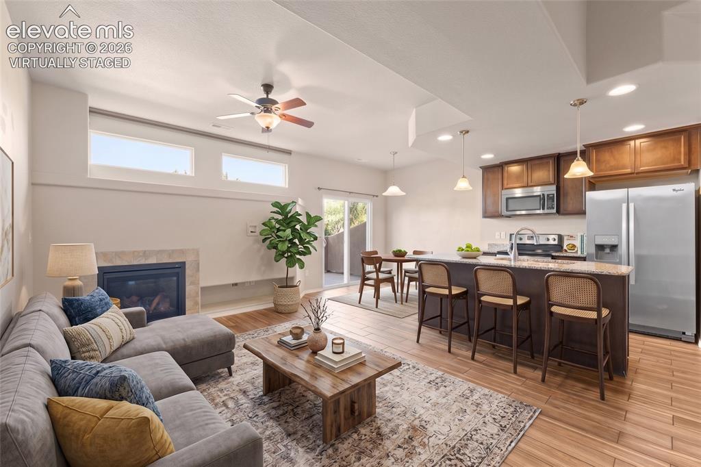 Image 10 of 42: Open-concept living area featuring a fireplace with stone surround, wood-fi