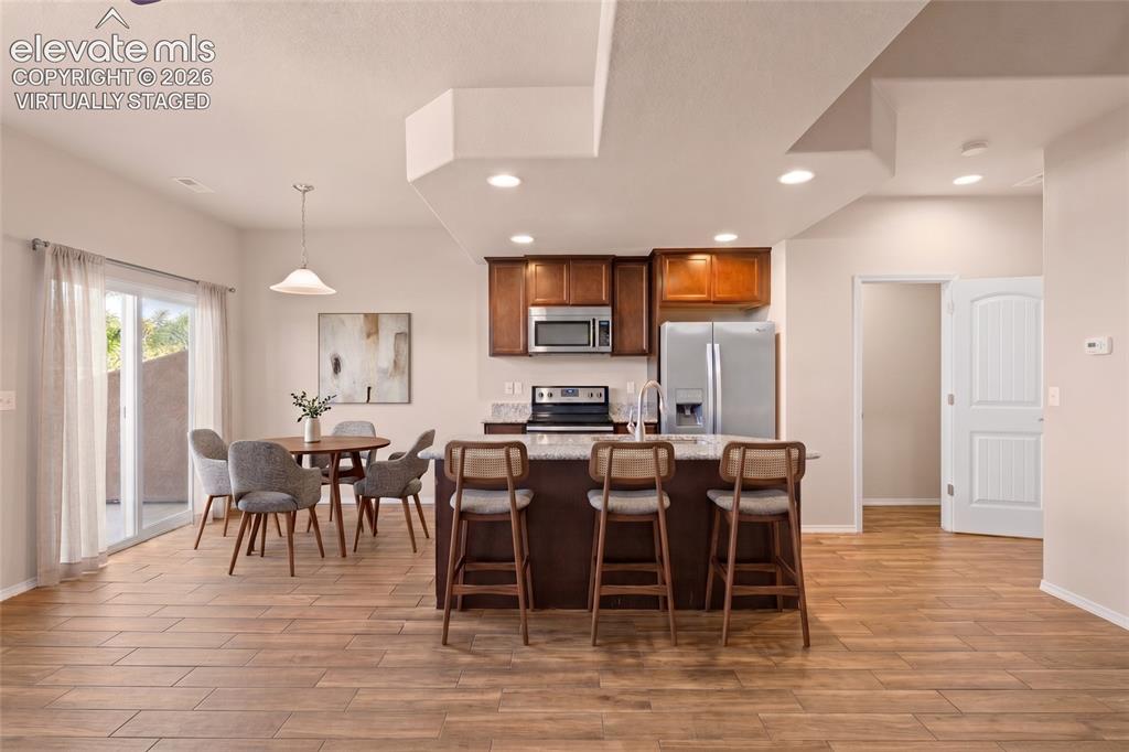 Image 14 of 42: Wood-finish flooring, recessed lighting, and a kitchen island with seating
