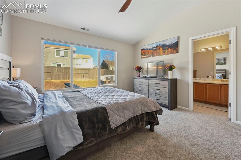 Image 17 of 24: Bedroom with vaulted ceiling, light carpet, ensuite bath, and ceiling fan