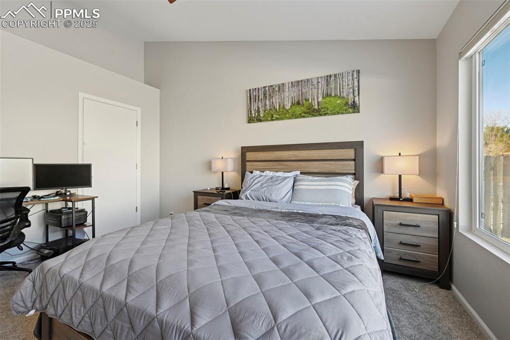 Image 19 of 24: Bedroom with carpet flooring, an office area, multiple windows, and vaulted