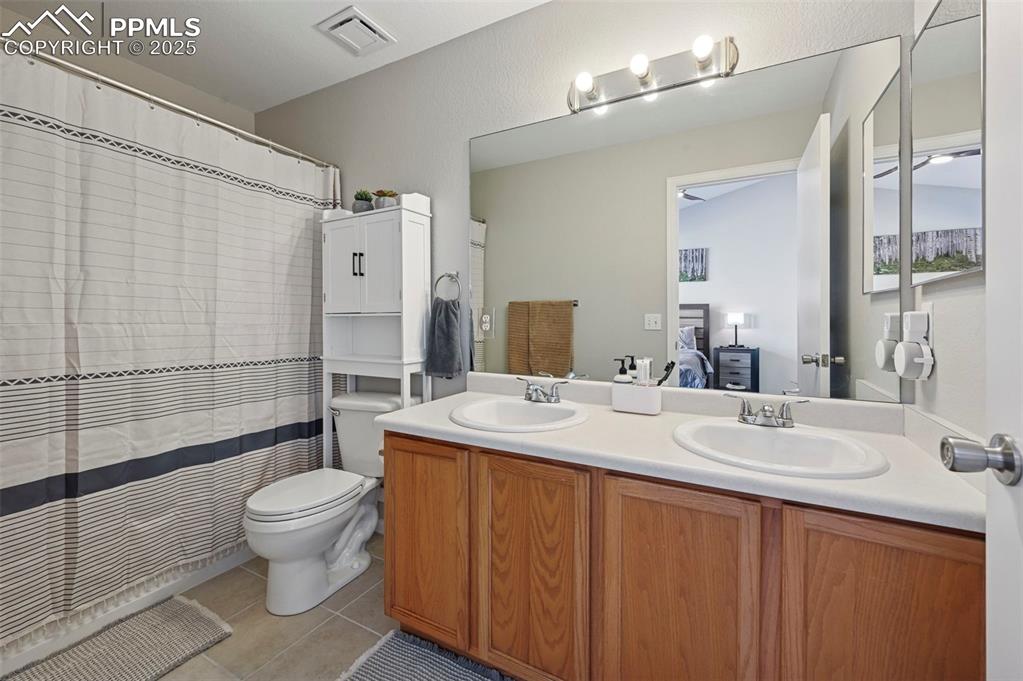 Image 20 of 24: Ensuite bathroom with a shower with shower curtain, double vanity, and ligh