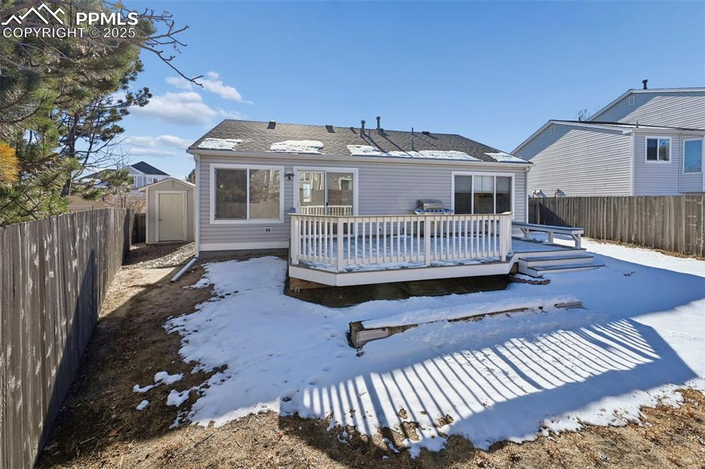 Image 23 of 24: Snow covered back of property with a shed, a fenced backyard, and a wooden 