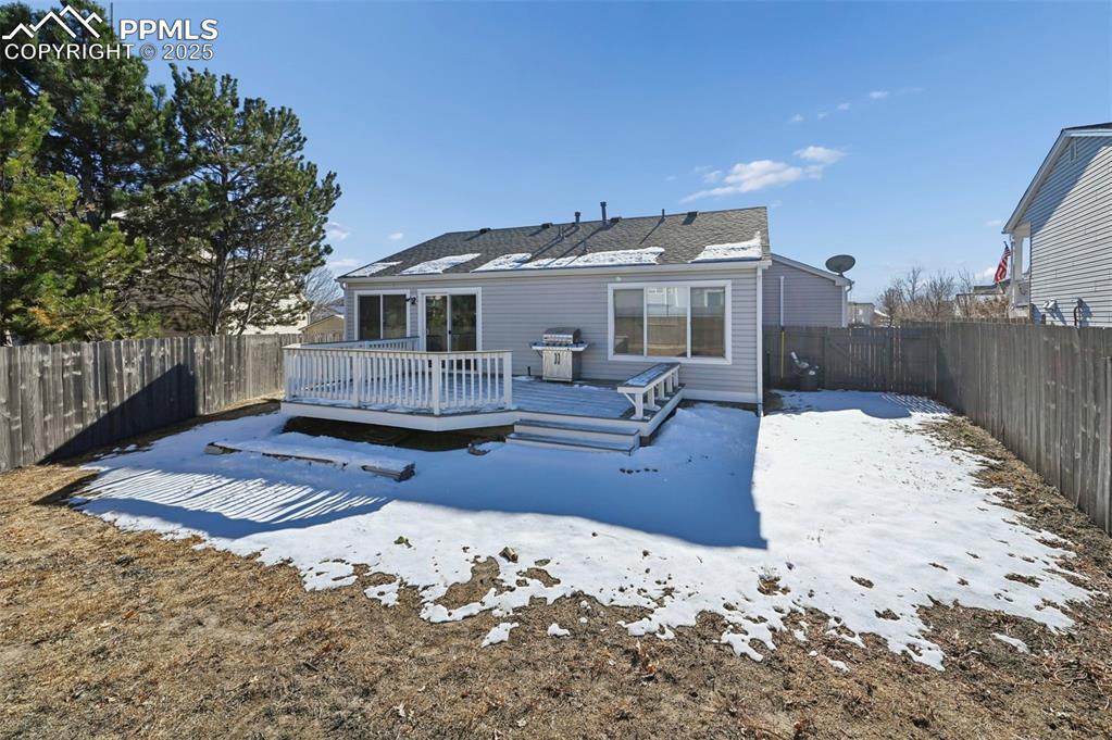 Image 24 of 24: Snow covered back of property with a fenced backyard and a wooden deck