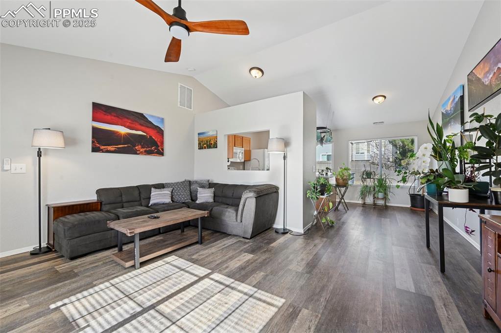 Image 5 of 24: Living area with a ceiling fan, vaulted ceiling, and wood finished floors