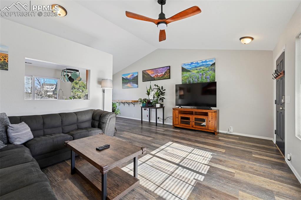 Image 6 of 24: Living area featuring a ceiling fan, lofted ceiling, and dark wood finished