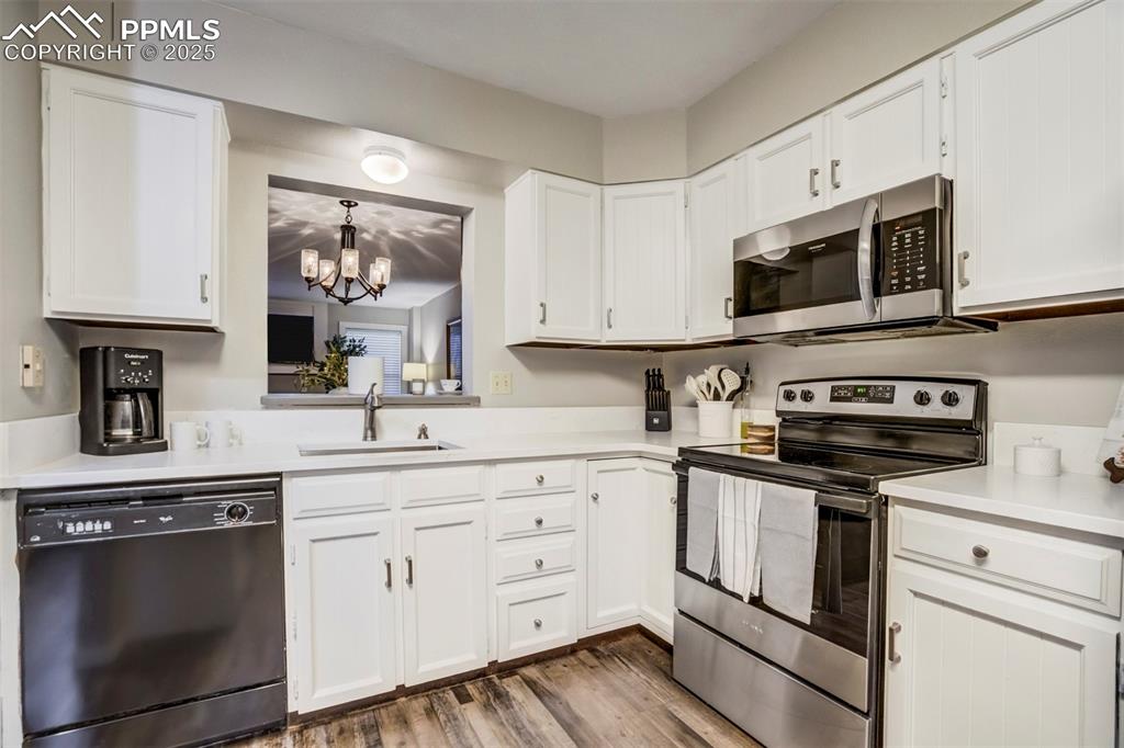 Image 13 of 31: Kitchen with stainless steel appliances, white cabinetry, a chandelier, and