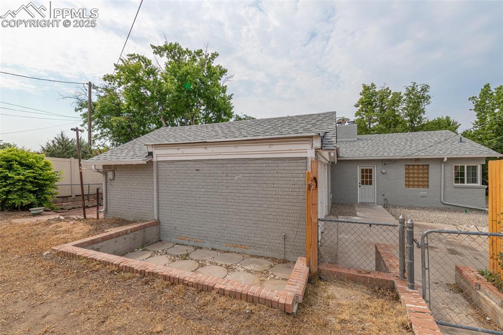 Image 33 of 35: View of front facade with a shingled roof, a gate, a fenced backyard, and b
