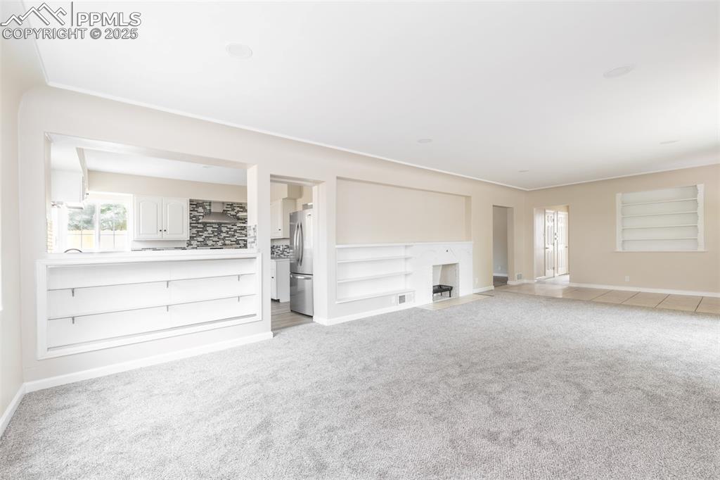Image 7 of 35: Unfurnished living room featuring light colored carpet and a fireplace with