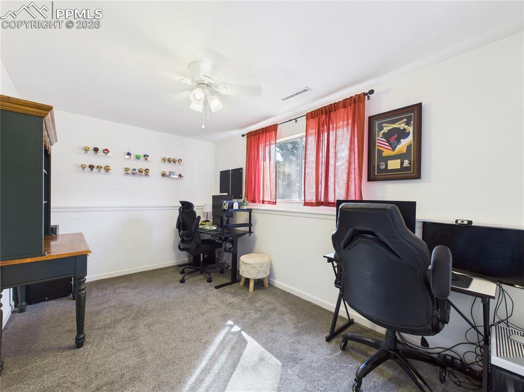 Image 24 of 39: Office space with light colored carpet and ceiling fan