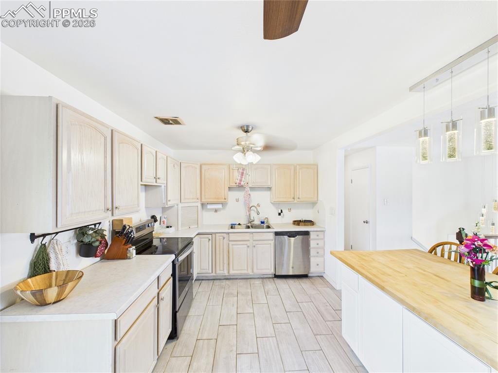 Image 8 of 39: Kitchen with stainless steel appliances, a ceiling fan, light wood finish c