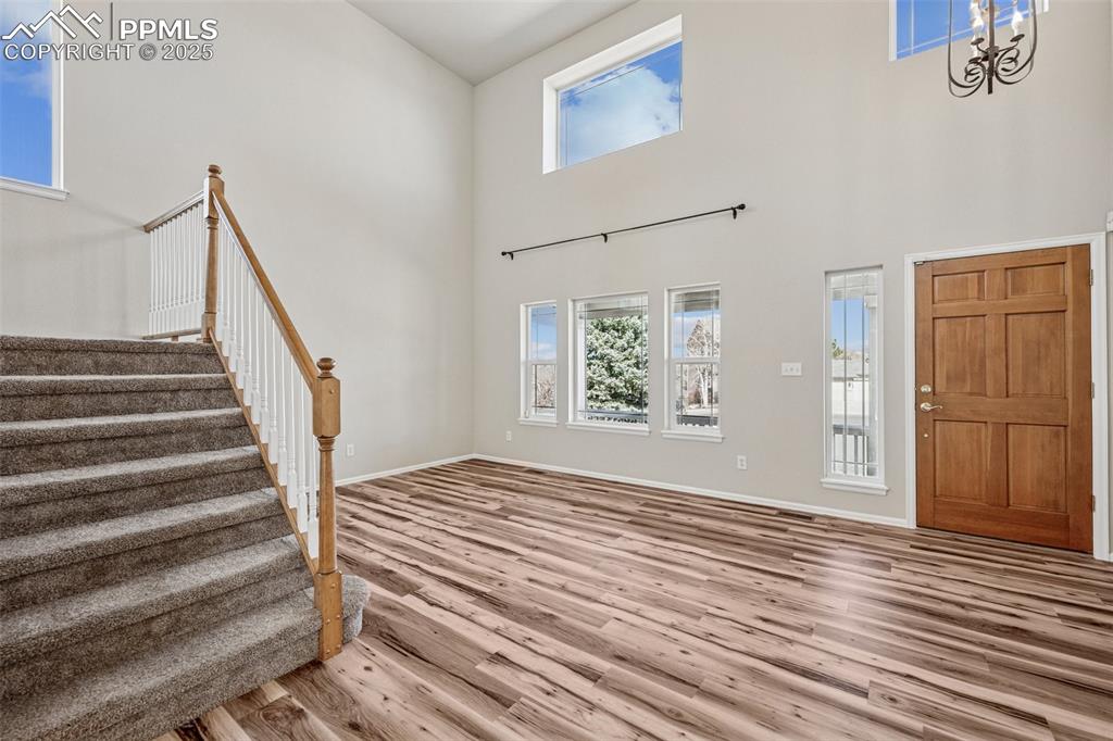 Image 16 of 43: Foyer entrance with wood finished floors, baseboards, an inviting chandelie