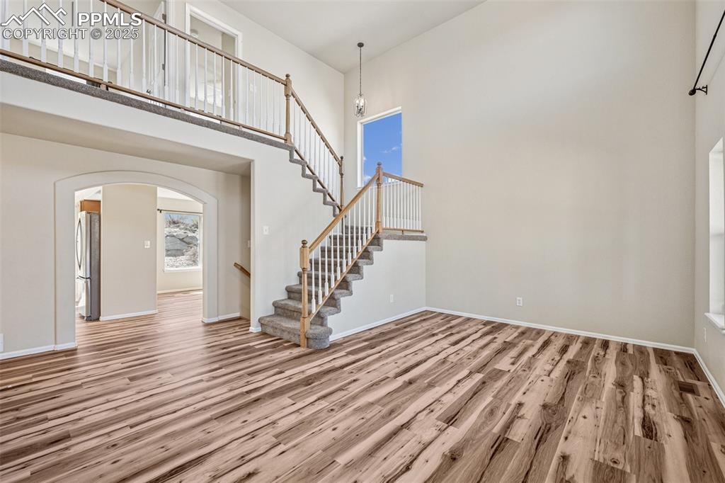 Image 17 of 43: Unfurnished living room featuring stairs, wood finished floors, arched walk