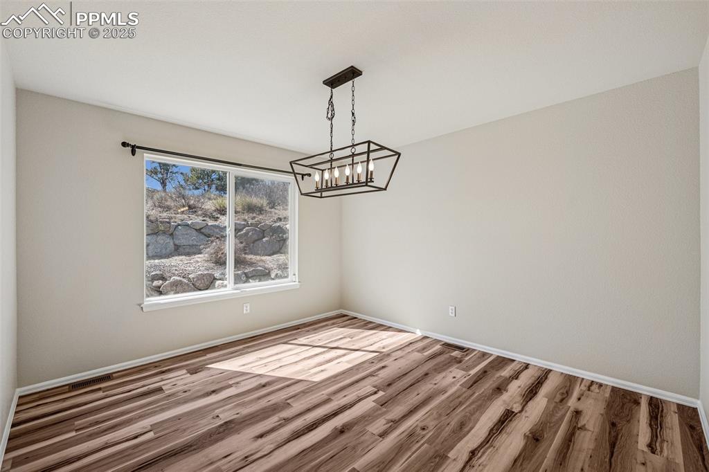 Image 18 of 43: Unfurnished dining area with a notable chandelier, baseboards, and wood fin