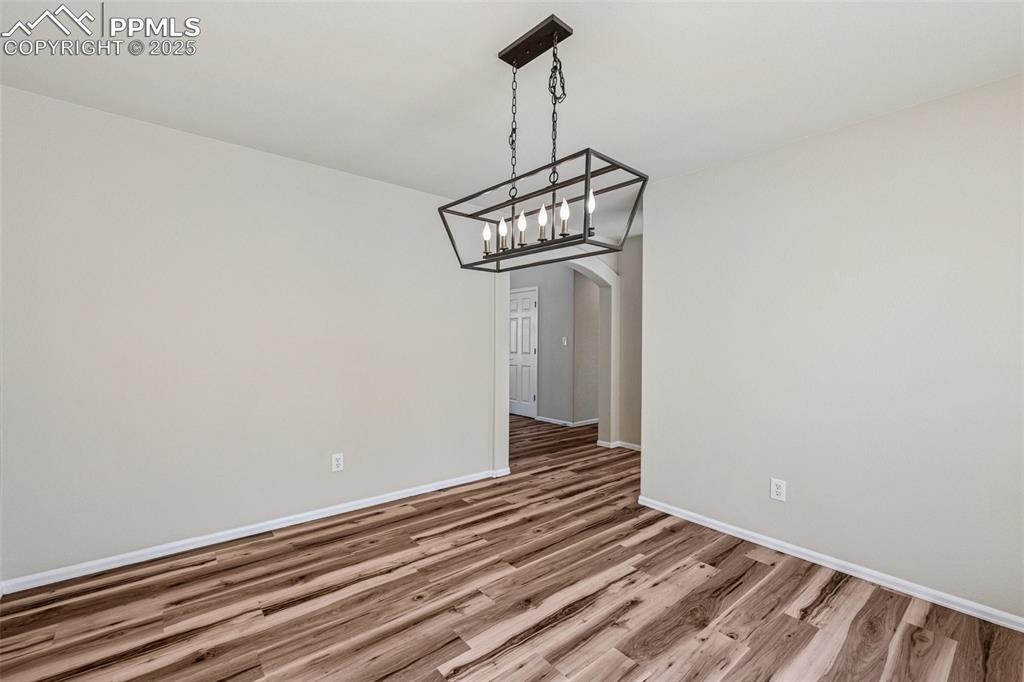Image 19 of 43: Unfurnished dining area with baseboards, arched walkways, an inviting chand