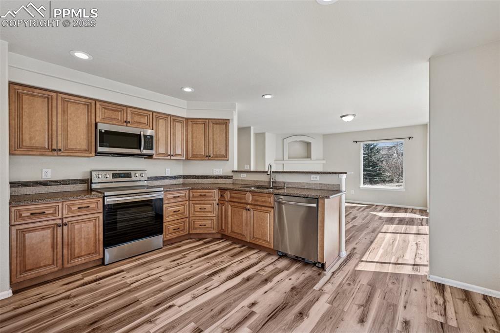 Image 21 of 43: Kitchen with light wood finished floors, recessed lighting, appliances with