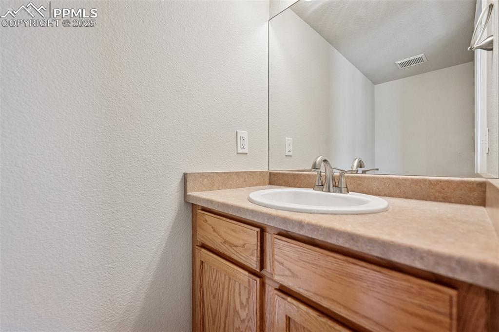 Image 26 of 43: Bathroom with visible vents, vanity, and a textured wall
