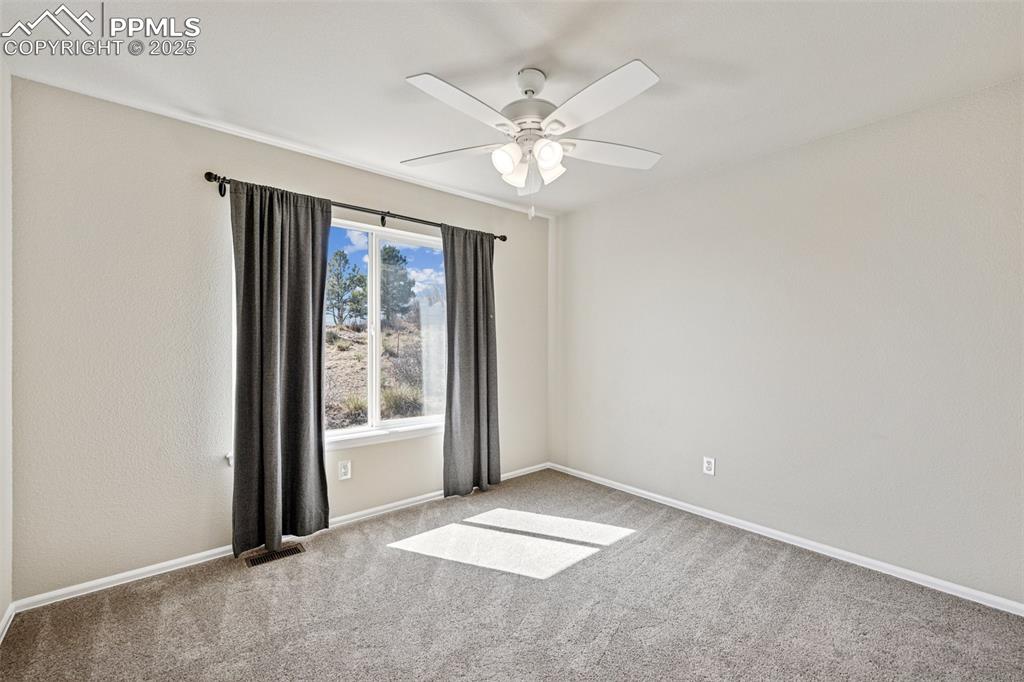 Image 30 of 43: Carpeted empty room with visible vents, a ceiling fan, and baseboards