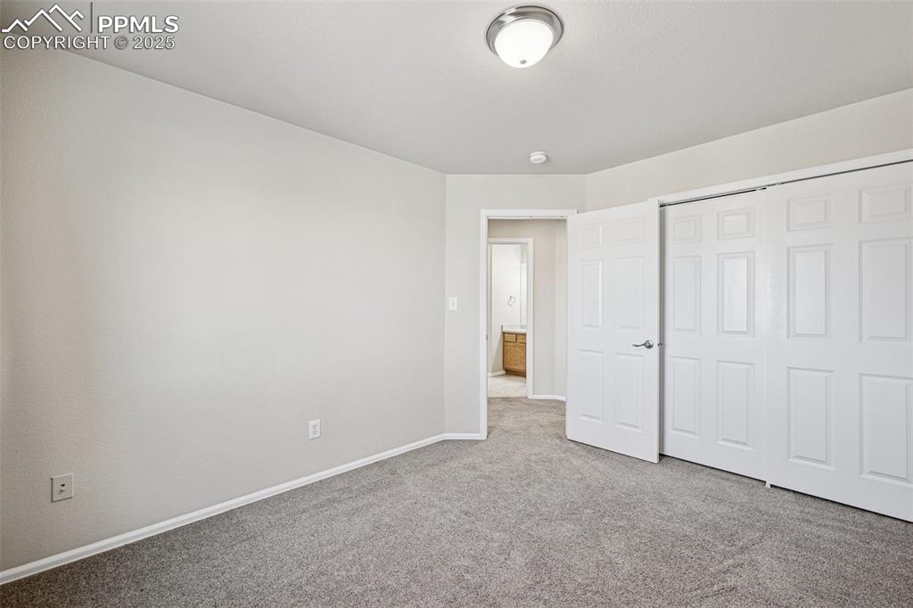 Image 33 of 43: Unfurnished bedroom with a closet, baseboards, and carpet flooring