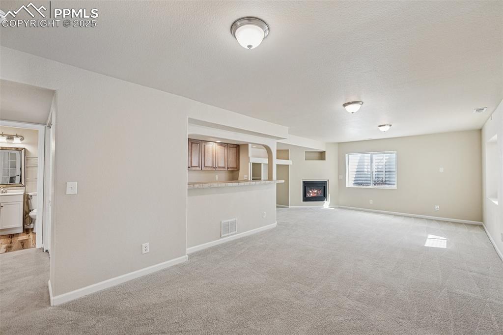 Image 37 of 43: Unfurnished living room featuring a glass covered fireplace, baseboards, vi