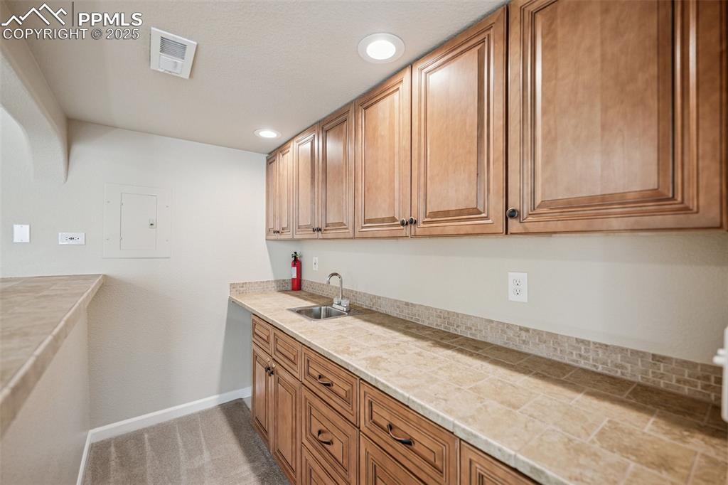 Image 38 of 43: Wet bar in basement with recessed lighting, light countertops, and baseboar
