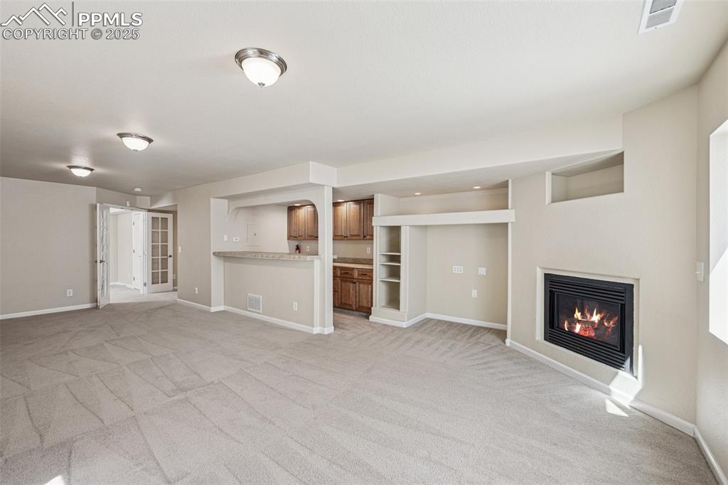 Image 4 of 43: Unfurnished living room with a glass covered fireplace, light colored carpe