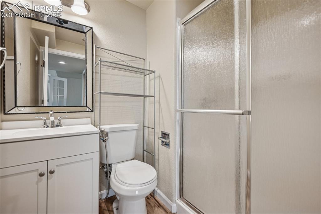 Image 43 of 43: Bathroom featuring a shower stall, toilet, wood finished floors, a textured