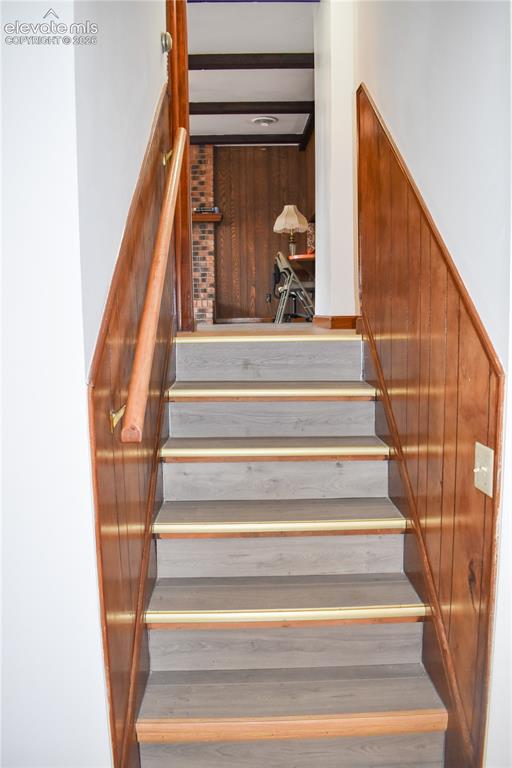 Image 12 of 44: Staircase featuring wood-finish treads with brass-tone nosing, wood panelin