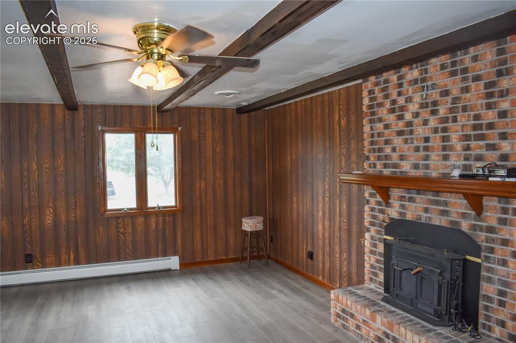 Image 14 of 44: Brick fireplace with a wood-finish mantel and a built-in stove