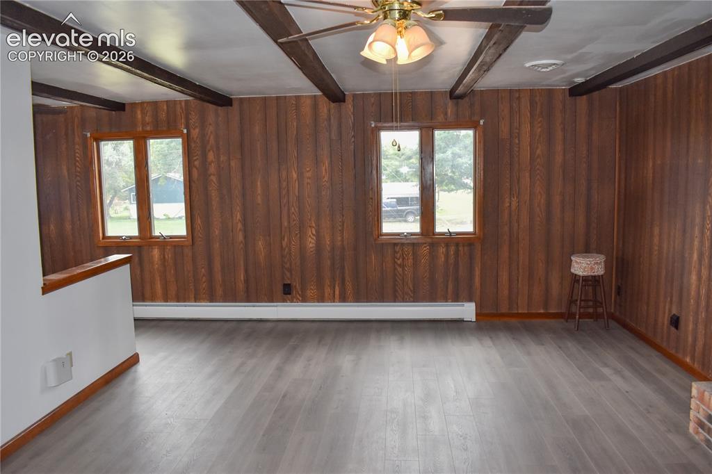 Image 15 of 44: Wood-finish paneling, exposed ceiling beams, ceiling fan with integrated li