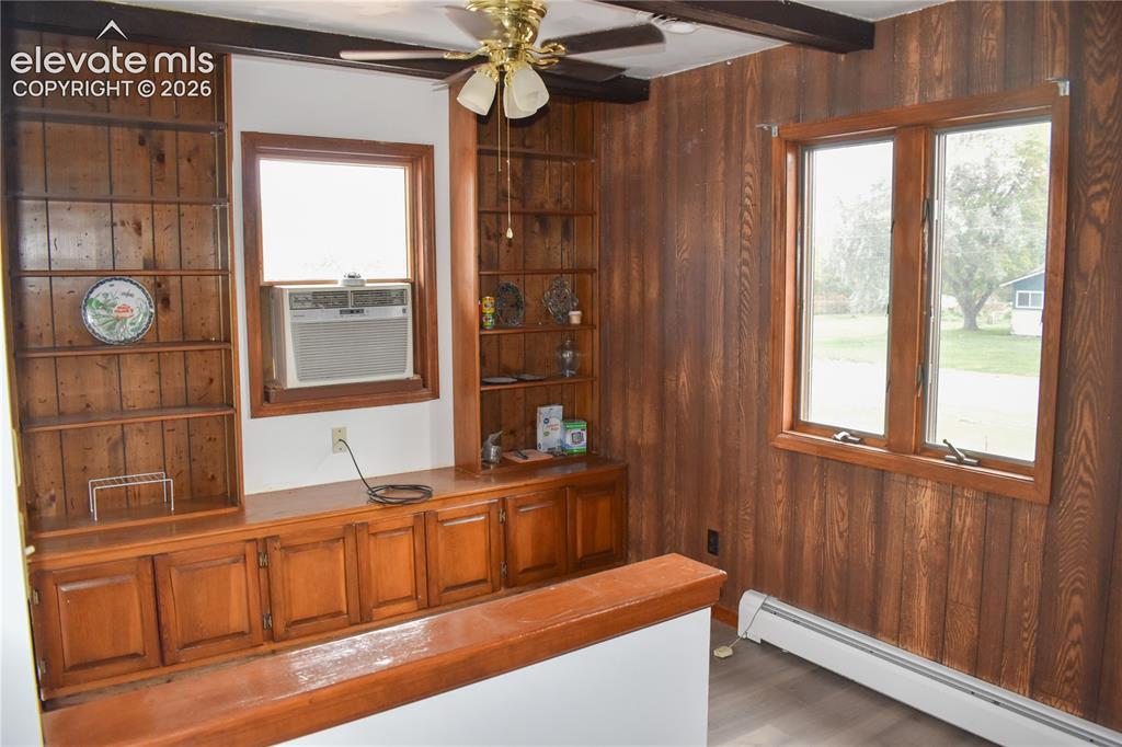 Image 17 of 44: Built-in wood shelving and cabinetry, wood paneling, exposed ceiling beams,