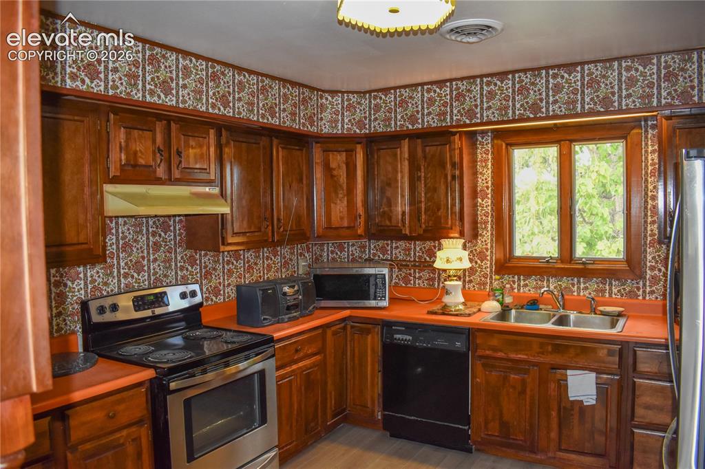 Image 18 of 44: Wood-finish cabinetry paired with orange-hued countertops
