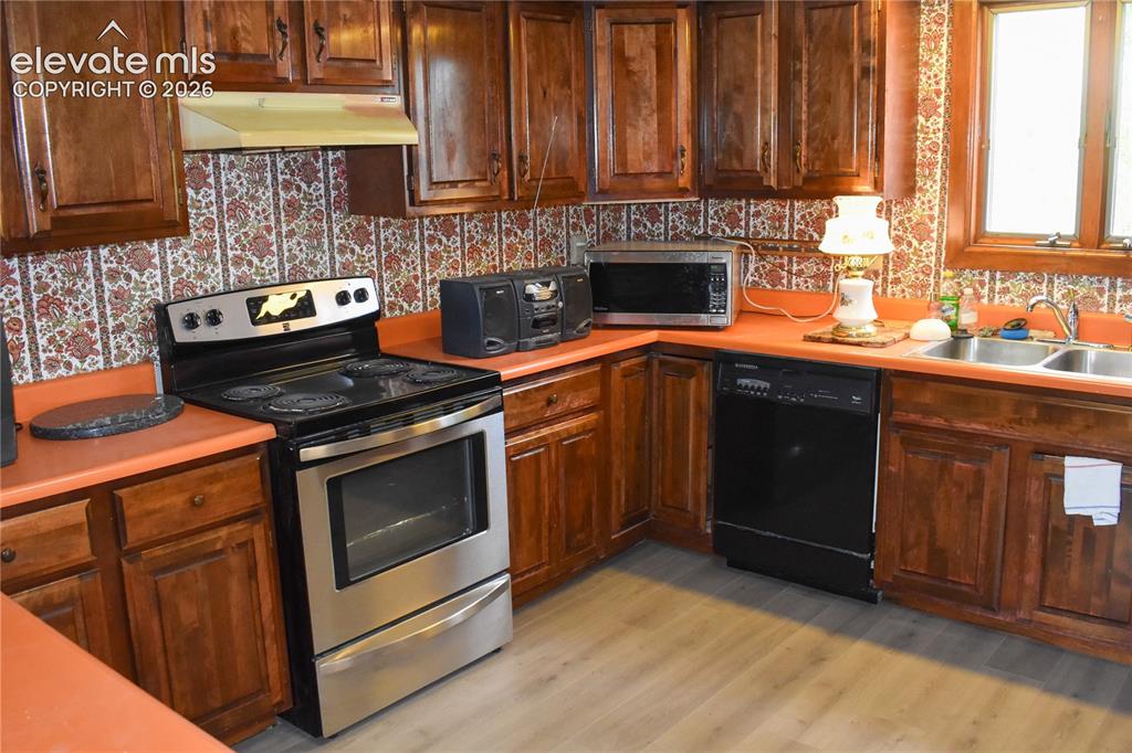 Image 19 of 44: Wood-finish cabinetry paired with a stainless steel range, a dual-basin sin