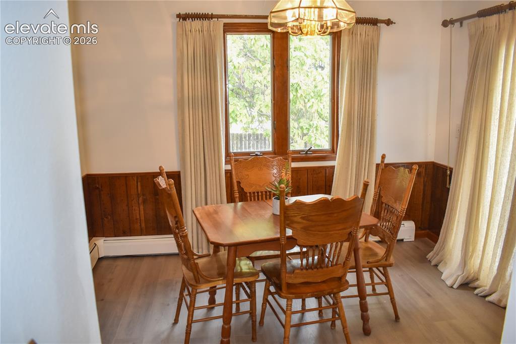 Image 21 of 44: Wood-finish flooring with wainscoting and natural wood window trim