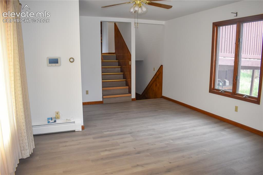 Image 22 of 44: Spacious room featuring wood-finish flooring, a ceiling fan, and a large wi