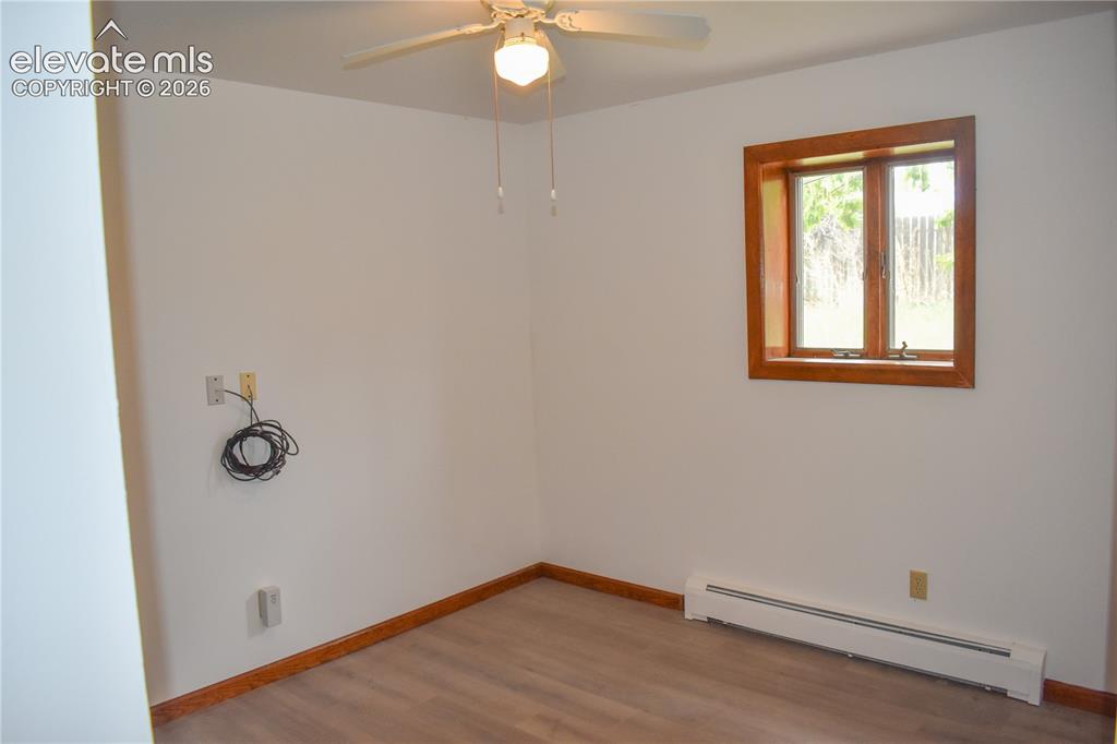 Image 23 of 44: Neutral wall paint with wood-finish flooring, a window featuring wood trim,