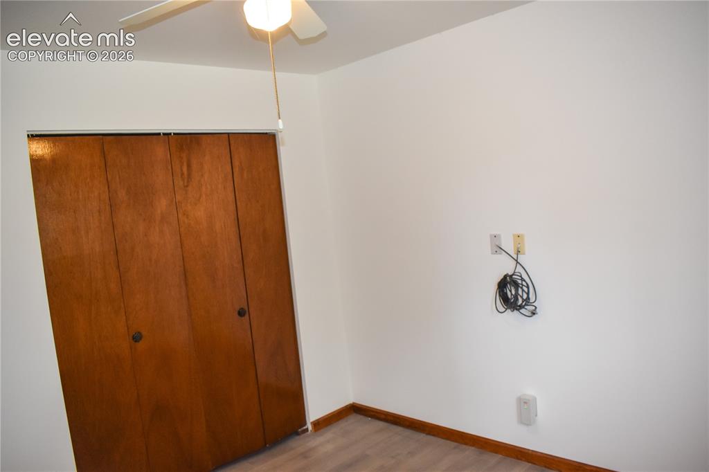 Image 24 of 44: White walls with a ceiling fan light fixture, wood-finish flooring, and woo