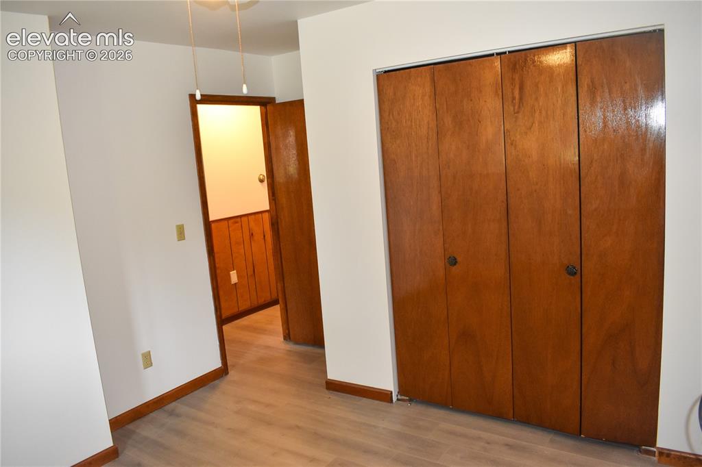 Image 25 of 44: Light wood-finish flooring, white painted walls, wood trim, and a built-in