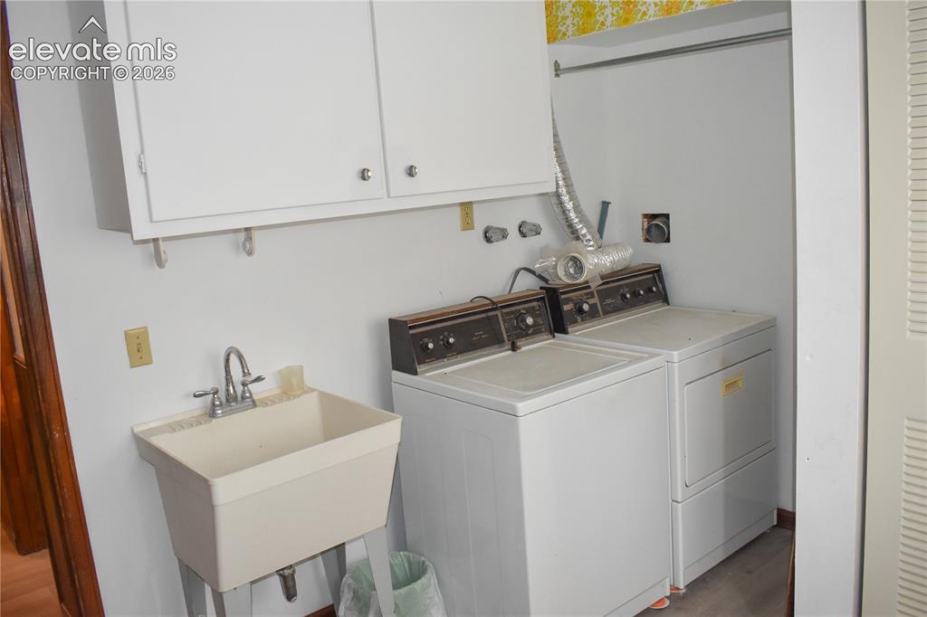 Image 30 of 44: Utility area featuring wall-mounted cabinetry, a utility sink with dual-han